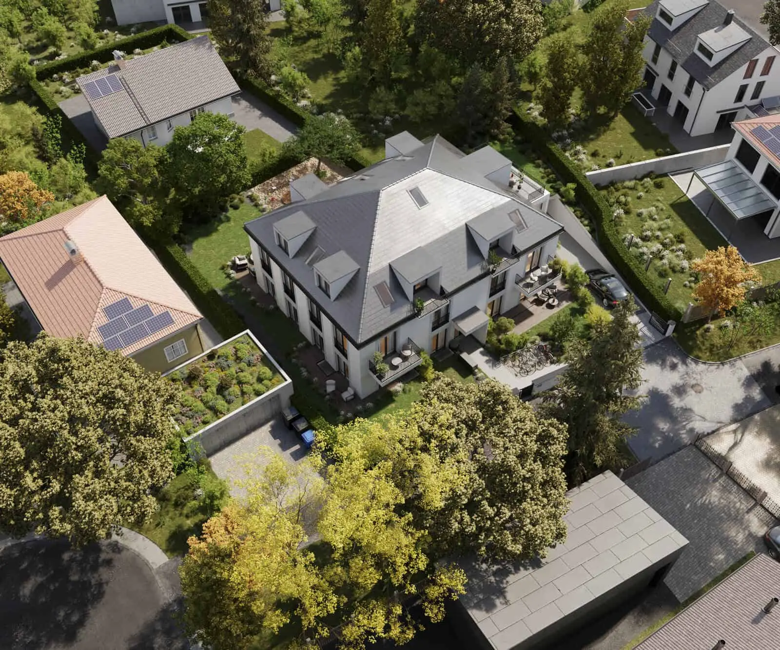 Aerial view of a modern residential building with balconies, surrounded by trees, gardens, and neighboring houses in a suburban area.