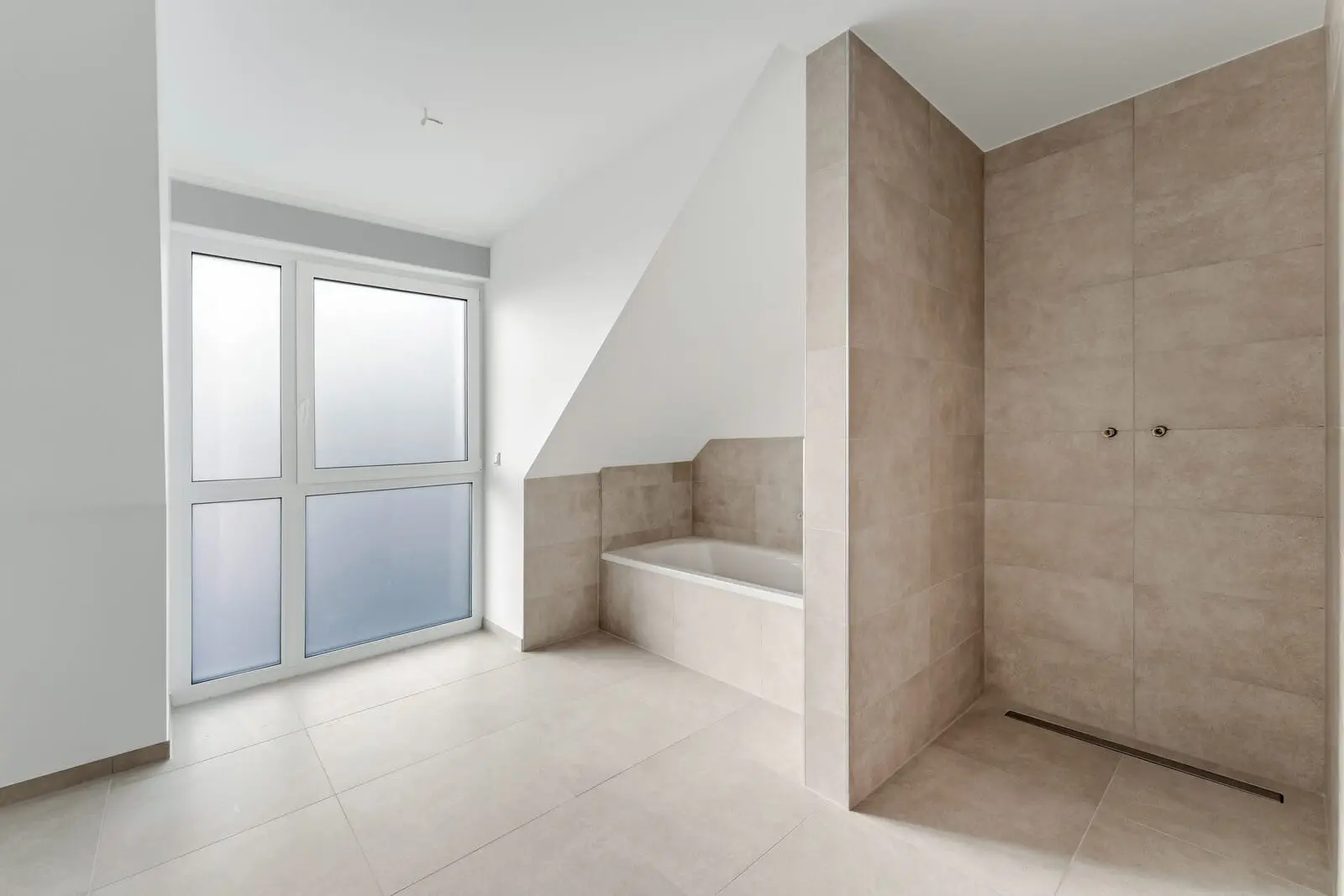 A modern bathroom with beige tiles, a built-in bathtub, a walk-in shower, and large frosted glass windows.