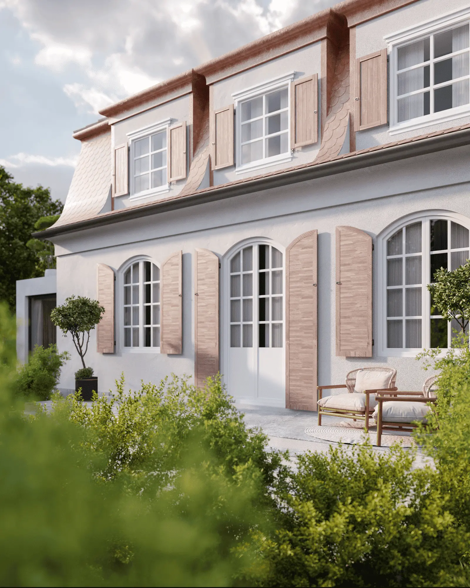 A two-story house with wooden shutters and white-framed windows, surrounded by greenery and featuring an outdoor seating area.